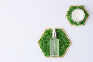 Cosmetic skin care products with a wooden hexagon and moss on white background. Flat lay, copy space photo