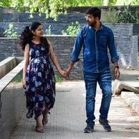 Indian couple posing for maternity baby shoot. The couple is posing in a lawn with green grass and the woman is falunting her baby bump in Lodhi Garden in New Delhi, India photo