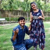 Indian couple posing for maternity baby shoot. The couple is posing in a lawn with green grass and the woman is falunting her baby bump in Lodhi Garden in New Delhi, India photo