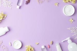 productos cosméticos para el cuidado de la piel con flores sobre fondo rosa. endecha plana, espacio de copia foto