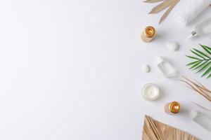 Spa treatment with cosmetic bottle, candles and palm leaf on white background. Flat lay, copy space photo