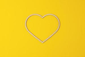 Cosmetic background with a wooden heart on yellow. Flat lay, copy space photo