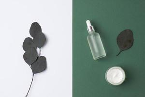 Minimal composition with cosmetic skin care products and eucalyptus on green background. Flat lay. photo