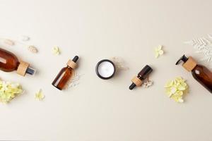 Cosmetic skin care products with flowers on pastel beige background. Flat lay, copy space photo