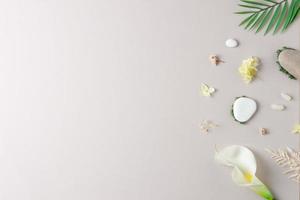 Cosmetic background with flowers, moss and stone on grey. Flat lay, copy space photo