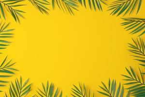 Yellow background with palm leaves. Flat lay, copy space photo