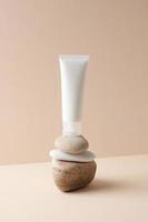 White tube of cosmetic cream on a stone podium on beige background. Close up. photo