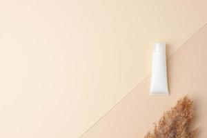 White tube of cosmetic cream on pastel beige background. Flat lay, copy space. photo