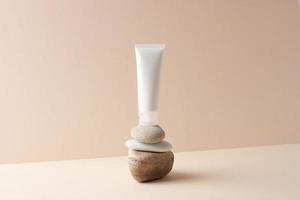 White tube of cosmetic cream on a stone podium on beige background. Close up. photo