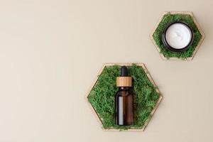 Cosmetic skin care products with a wooden hexagon and moss on pastel beige background. Flat lay, copy space photo