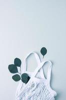 Zero waste, sustainable and eco-friendly lifestyle. Basket and eucalyptus on grey background. Flat lay, copy space photo