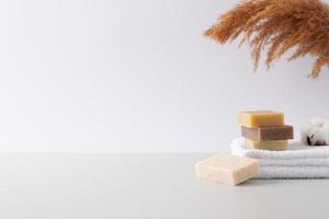 Spa treatment with soap, towel and flowers on white background. Close up, copy space photo