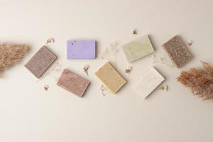 Soap and flower on beige background. Flat lay, copy space. photo