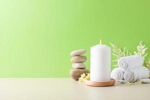 Spa treatment with candles, towel and flowers on green background. Close up, copy space photo