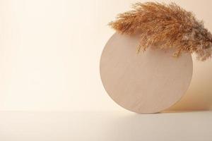 Cosmetic background with wooden and pampas on pastel beige. Empty showcase for cosmetic product presentation. photo