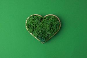 Cosmetic background with a wooden heart and moss on green. Flat lay, copy space photo