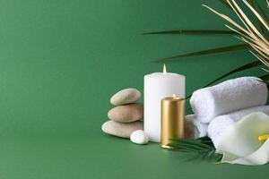 Spa treatment with herbal bag, candles and palm leaf on green background. Close up, copy space photo