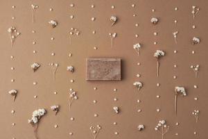 Soap and flower on brown background. Flat lay, copy space. photo