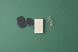 Soap with flowers on green background. Flat lay, copy space. photo