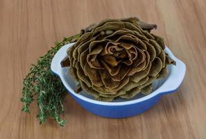 Boiled artichokes in a bowl on wooden background photo