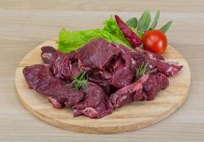 Raw venison on wooden board and white background photo