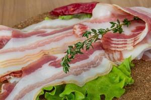 Bacon on wooden board and white background photo