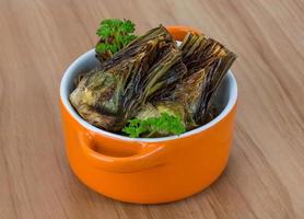 Grilled artishokes in a bowl on wooden background photo