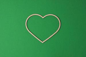 Cosmetic background with a wooden heart on green. Flat lay, copy space photo