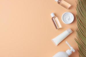productos cosméticos para el cuidado de la piel con hoja de palma sobre fondo beige pastel. endecha plana, espacio de copia foto
