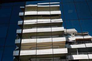 Modern office building design, facade geometry with reflection, blue glass windows repetition, pattern, geometric architectural symmetry, minimalist urban architecture. photo