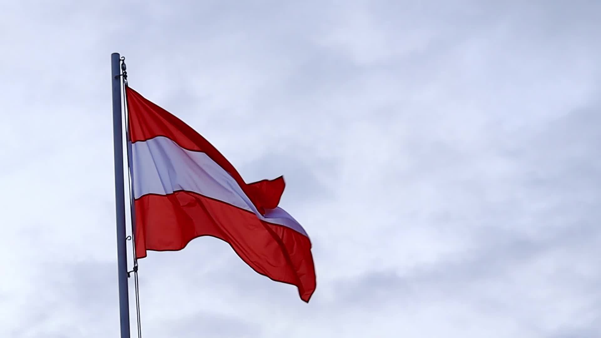 Die österreichische Fahne weht im Wind vor blauem Himmel. Flagge