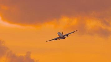 Passenger airplane flying at sunset. Long shot of an airliner taking off gaining altitude. Cinematic footage of a jet plane in the sunset fire sky video