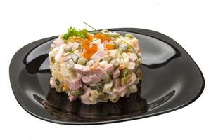 ensalada rusa en el plato y fondo blanco foto