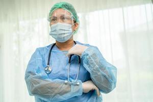 Asian doctor wearing face shield and PPE suit new normal to check patient protect safety infection Covid 19 Coronavirus outbreak at quarantine nursing hospital ward. photo