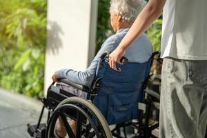 cuidador ayuda y cuida a una anciana asiática o anciana sentada en silla de ruedas para ir a la rampa en el hospital de enfermería, un concepto médico fuerte y saludable. foto