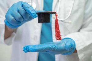 el estudio de un médico asiático aprende con un sombrero de brecha de graduación en la sala del hospital, un concepto de medicina inteligente y brillante. foto