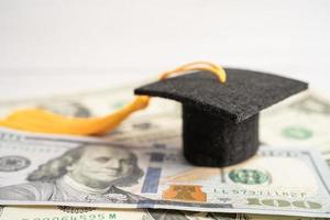 sombrero de la brecha de graduación en el dinero de los billetes en dólares estadounidenses, concepto de enseñanza de aprendizaje de la tarifa de estudio de educación. foto