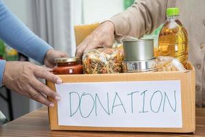 Volunteers putting various dry food in donation box for help people. photo
