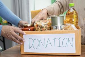 voluntarios poniendo varios alimentos secos en cajas de donación para ayudar a las personas. foto