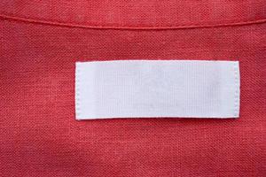 White blank clothing tag label on red linen shirt fabric texture background photo