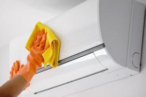 Asian man cleaning air conditioner with microfiber cloth photo