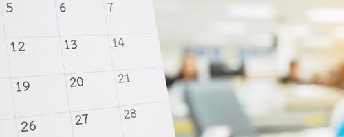 Close up white paper desk calendar on table with blurred office interior background photo