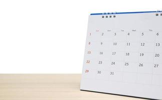 White desk calendar on wood table top isolated on white background photo