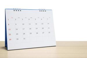 White desk calendar on wood table top isolated on white background photo