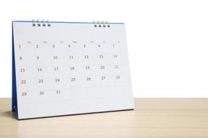 Calendario de escritorio blanco en la parte superior de la mesa de madera aislado sobre fondo blanco. foto