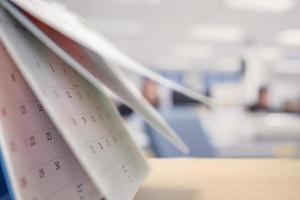 hoja de cambio de página del calendario en la mesa con el fondo interior de la oficina borrosa planificación de la programación de negocios concepto de reunión de cita foto