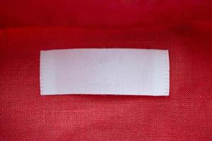 White blank clothing tag label on red linen shirt fabric texture background photo