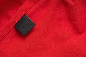 Blank black laundry care clothing label on red color fabric texture photo