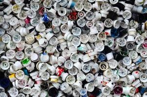 una gran cantidad de tapas de latas de pintura en aerosol para graffiti. manchadas con boquillas de pintura de colores yacen en una enorme pila foto