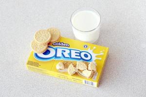 TERNOPIL, UKRAINE - MAY 28, 2022 Oreo golden crispy cookies with glass of milk on white background. The brand Oreo is owned by company Mondelez international photo